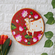 This beautiful pichwai painting features a serene white cow adorned with a vibrant floral headdress.
